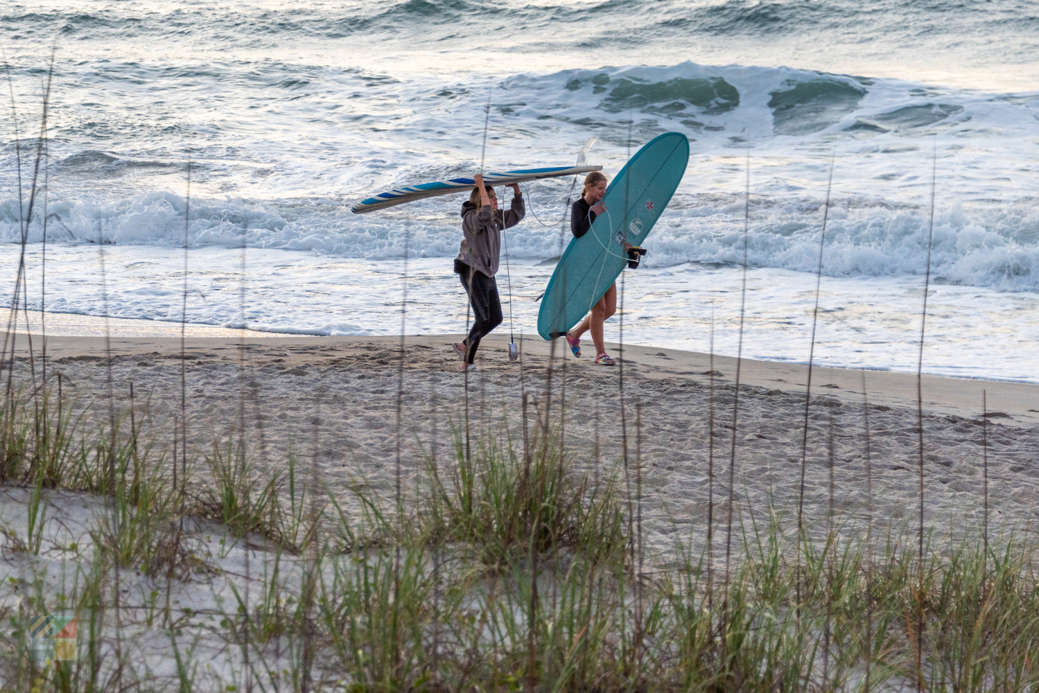 Surfers on the beach at sunrise